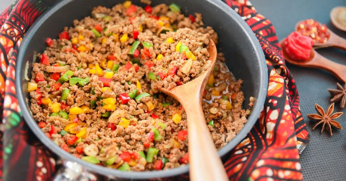 Picadillo vibrant cuit avec des poivrons rouges, verts et jaunes dans une poêle.