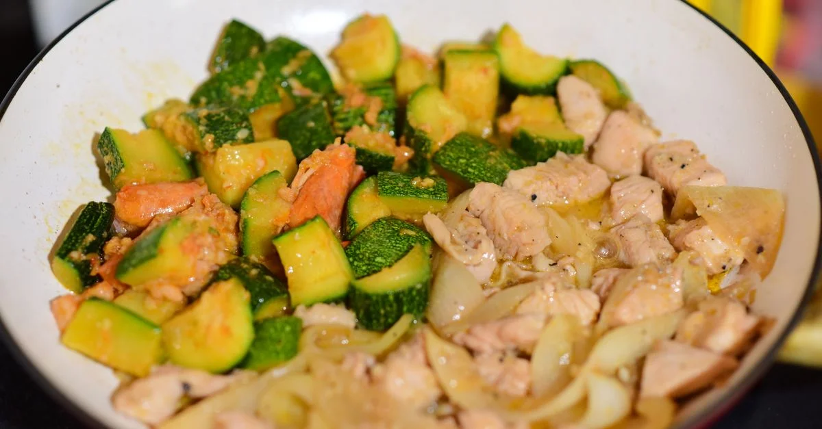 Mélange de poulet sauté et de courgette dans une poêle pour un repas sain.