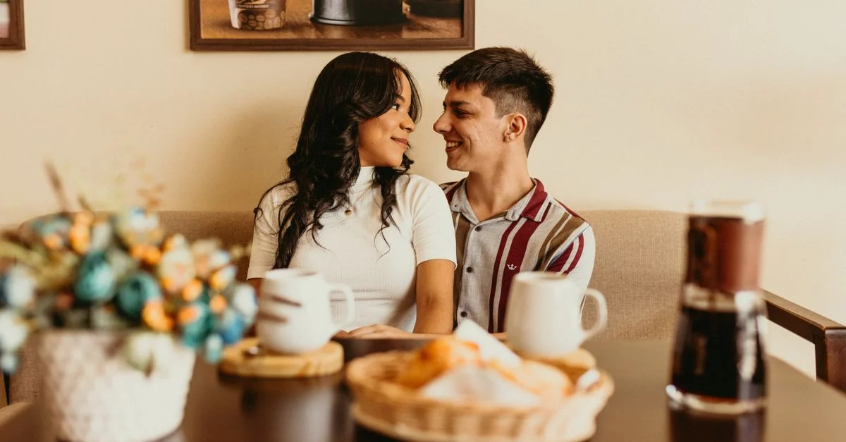 Un couple heureux se sourit dans un café intime, profitant de leur temps ensemble.