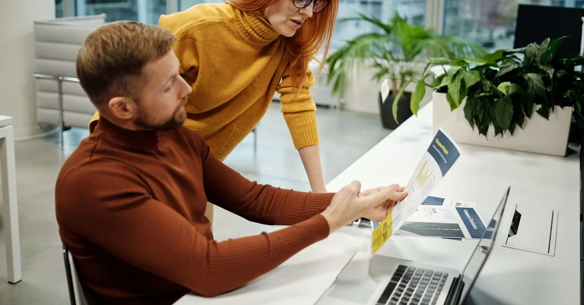 Deux collègues examinant des documents dans un bureau moderne, mettant l'accent sur le travail d'équipe et la collaboration.