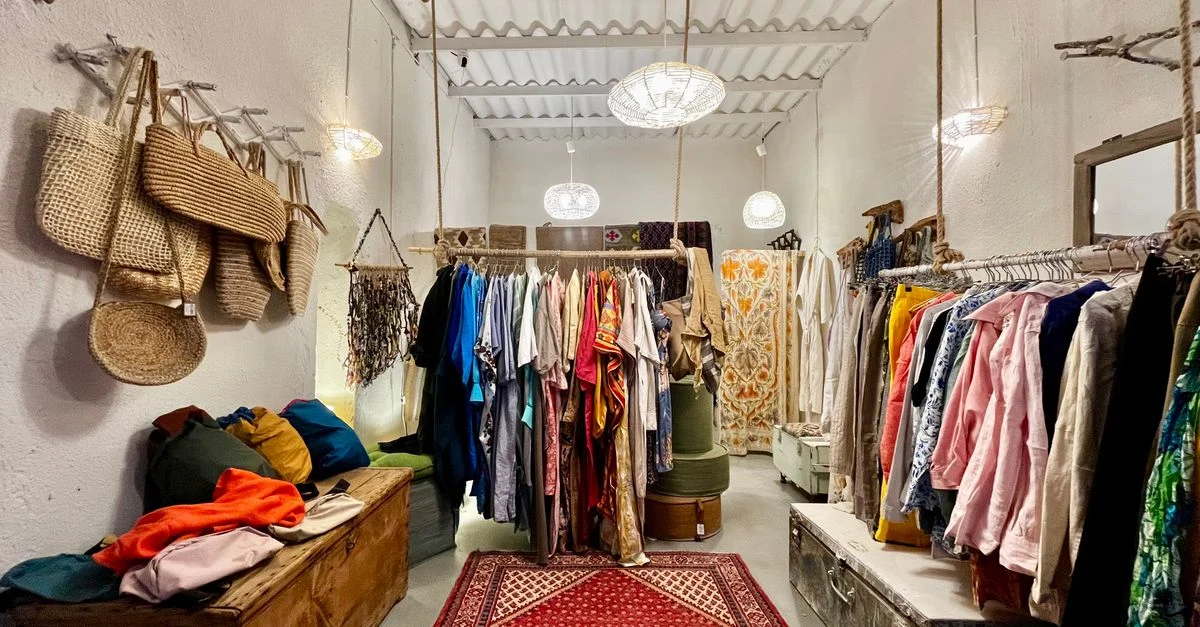 Intérieur de boutique éclectique présentant une vitrine de vêtements colorée et des accessoires tissés.