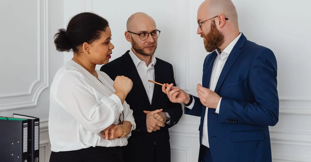 Trois professionnels engagés dans une discussion d'affaires dans un environnement de bureau.