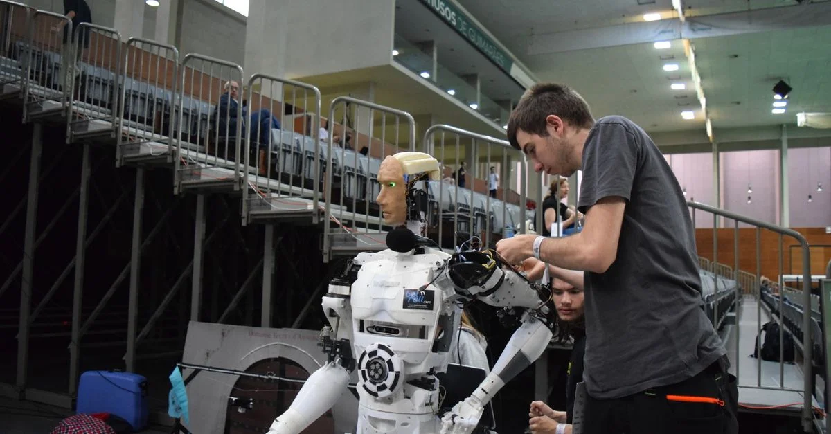 Technicien travaillant sur un robot humanoïde lors d'une exposition technologique à Guimarães, Portugal.