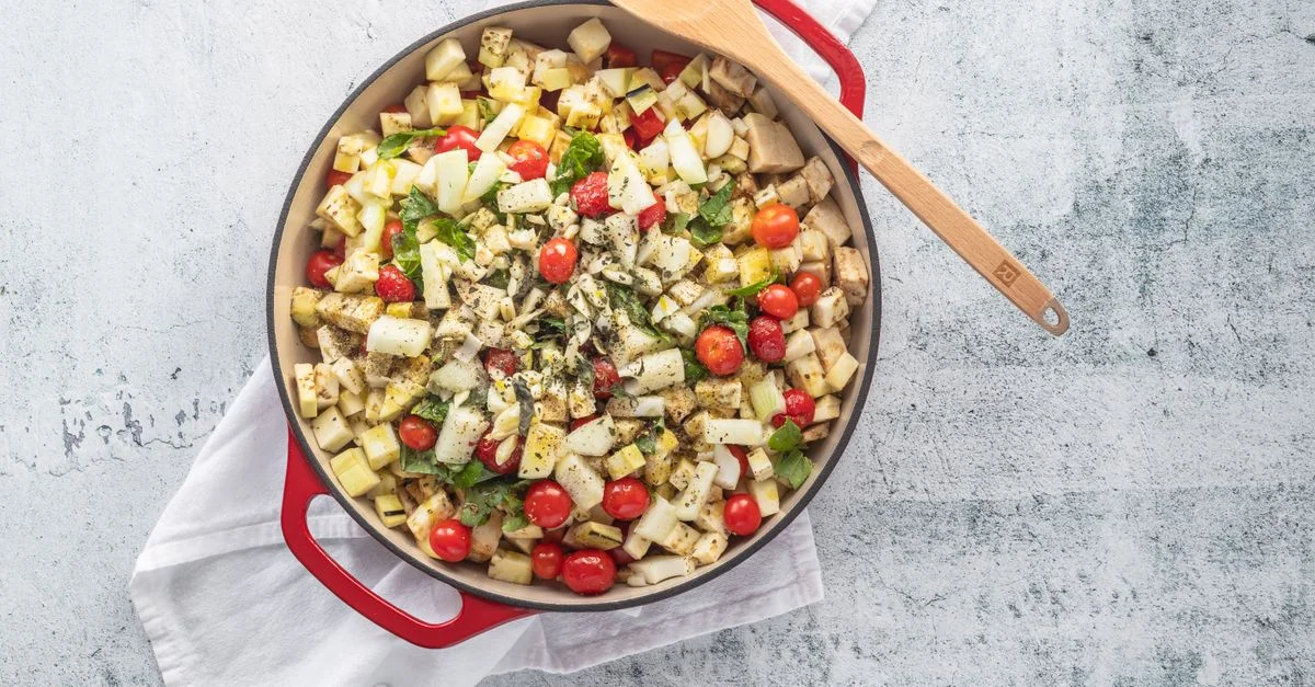 Plat végétal délicieux et coloré avec des tomates cerises dans une poêle rouge.