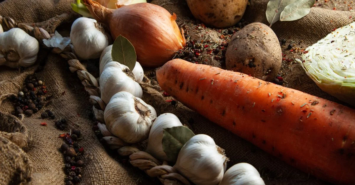 Une variété de légumes frais, comprenant des carottes, de l'ail et des pommes de terre, sur du jute rustique.