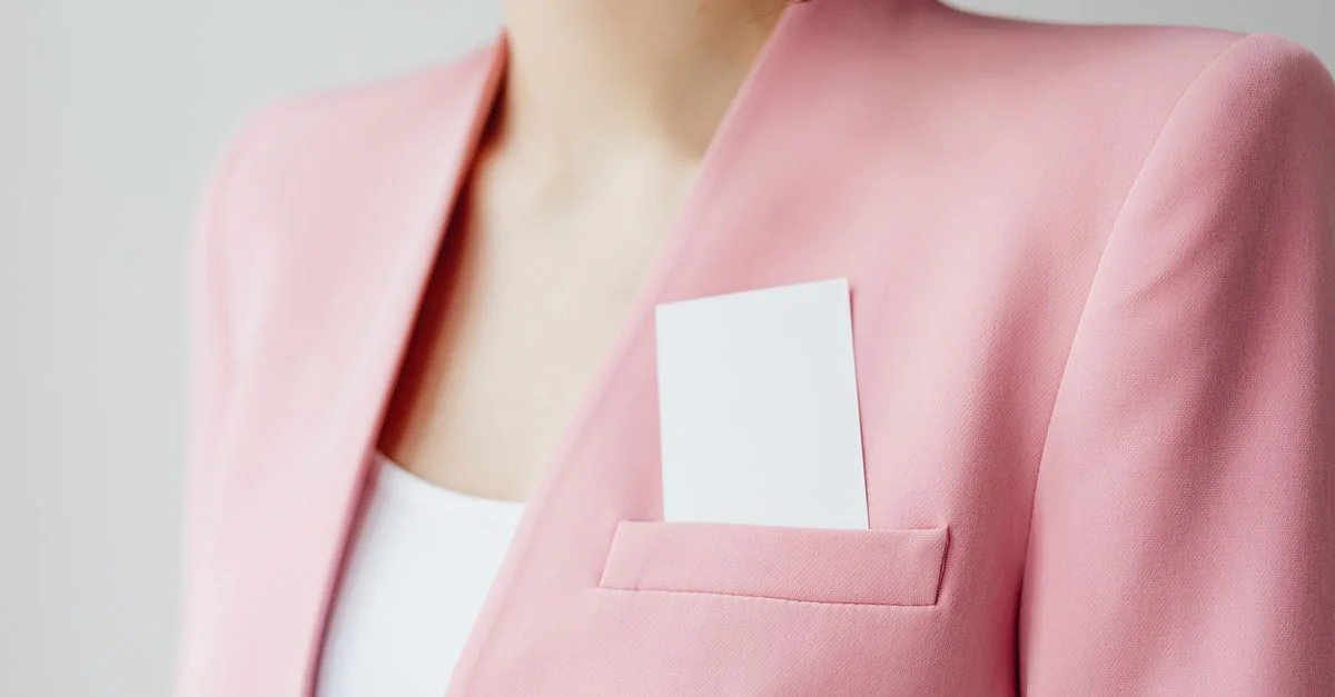 Élégant blazer rose avec carte de visite dans la poche pour un look professionnel.