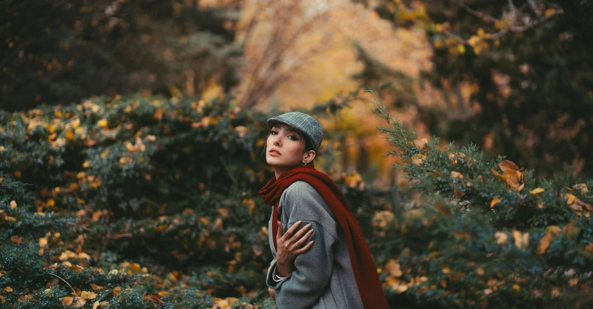 Femme élégante avec foulard dans une forêt d'automne pittoresque, illustrant l'élégance et la chaleur.