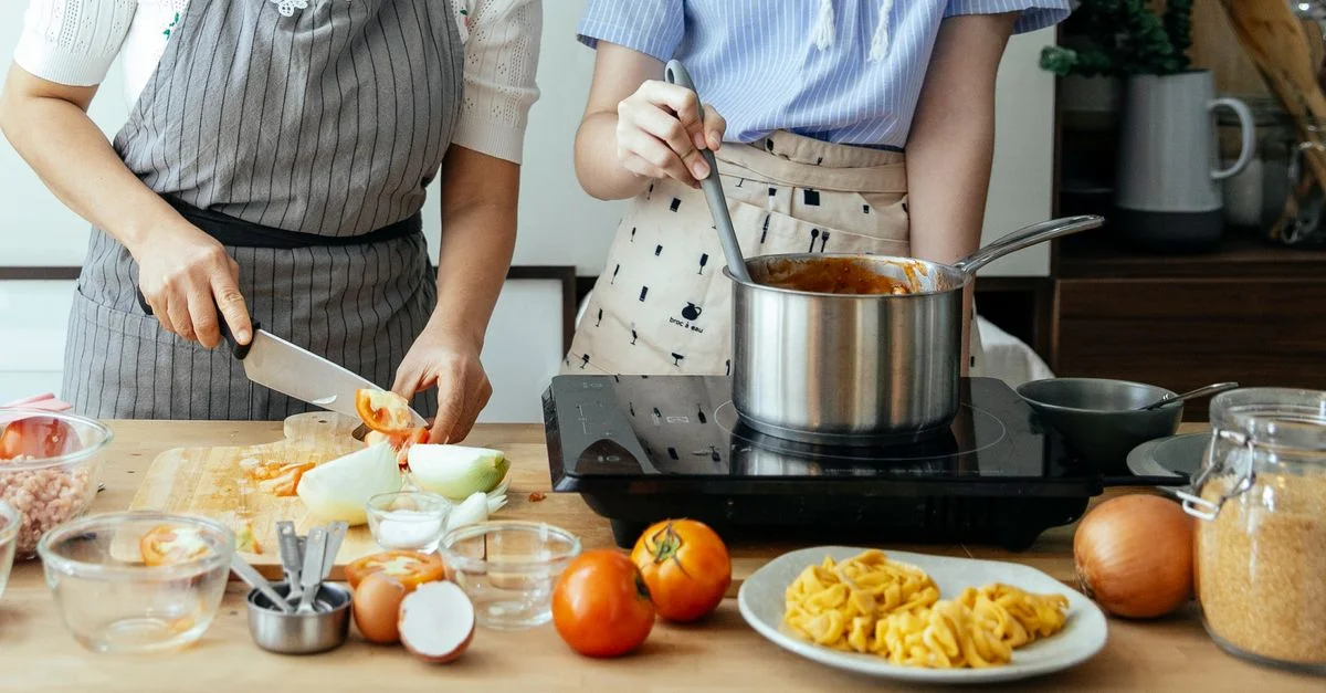 Deux personnes préparant un repas maison avec des ingrédients frais dans une cuisine.