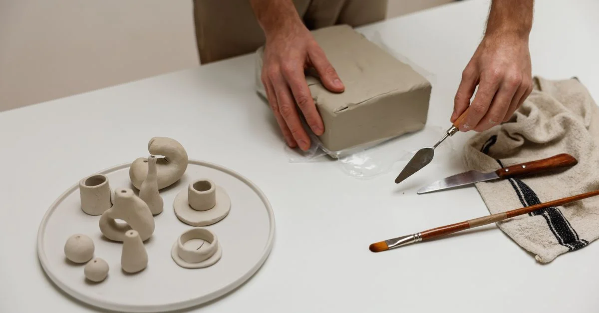 Gros plan sur des mains modelant de l'argile avec des outils dans un studio.