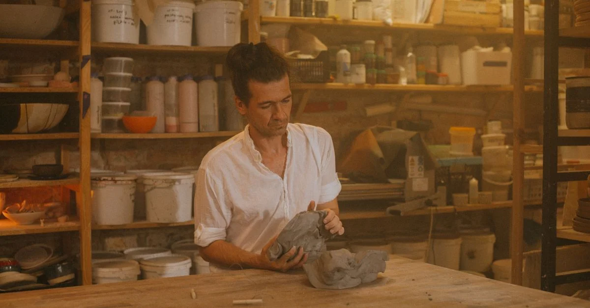 Un artisan sculpte habilement de l'argile dans un atelier chaleureux et accueillant, rempli de fournitures de poterie.